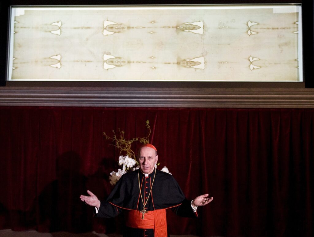 Cardinal Severino Poletto stands beneath the Shroud of Turin, at the Cathedral of Turin in Italy.