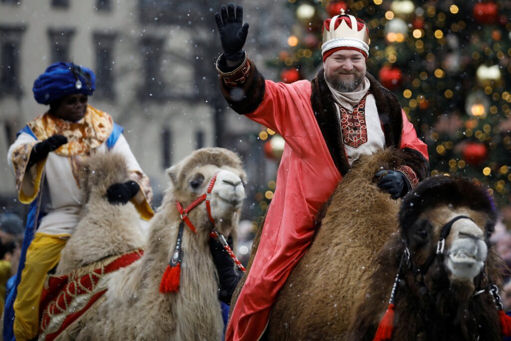 Two people representing two of the three wise men of the Epiphany story ride camels in a parade in Warsaw, Poland.