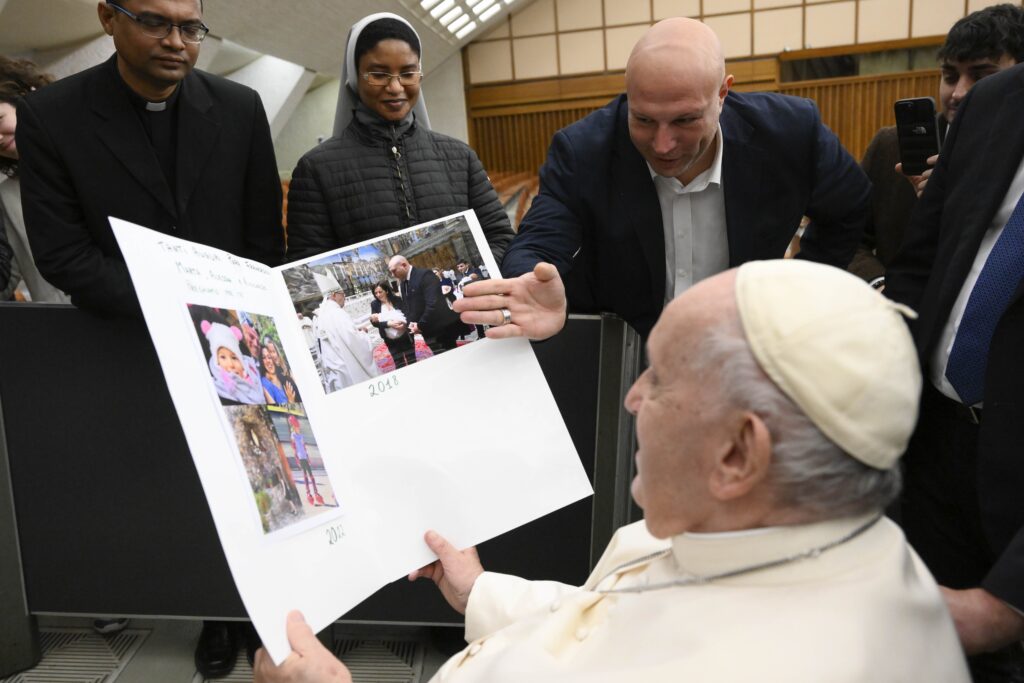 Pope Francis looks at photos from a Vatican employee whose daughter he baptized in 2018.