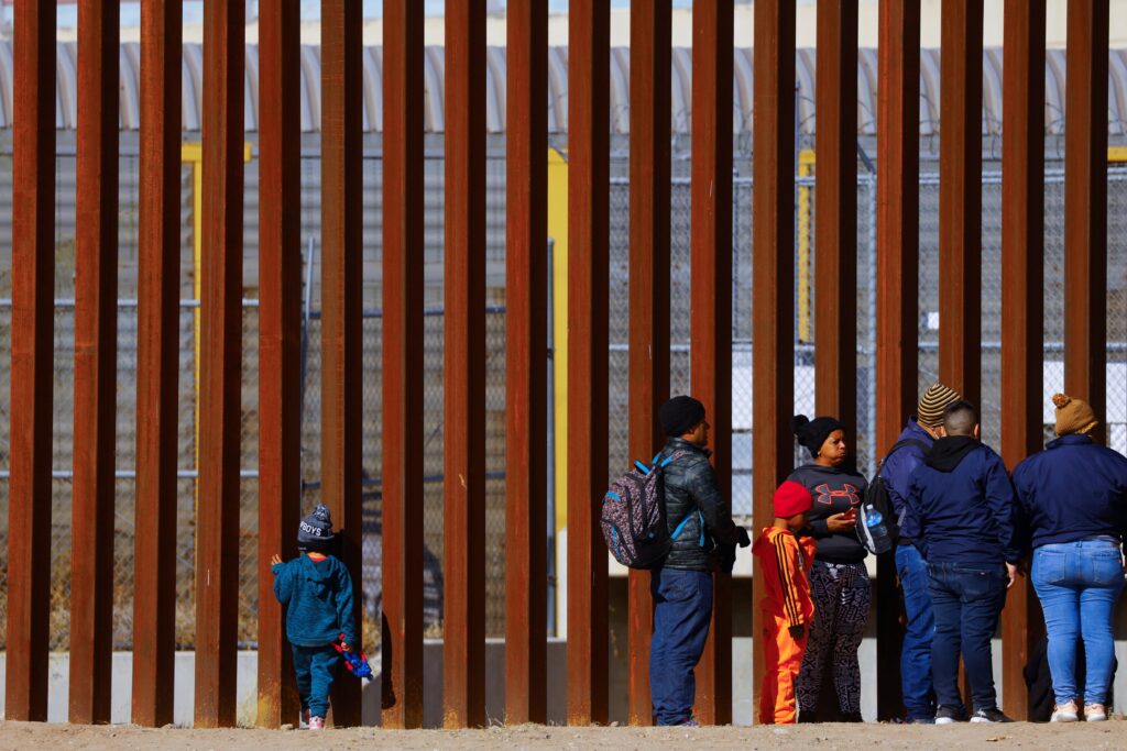 George, 5, a migrant boy from Venezuela traveling with his family, looks through the border wall as family members line up to request asylum in El Paso, Texas.