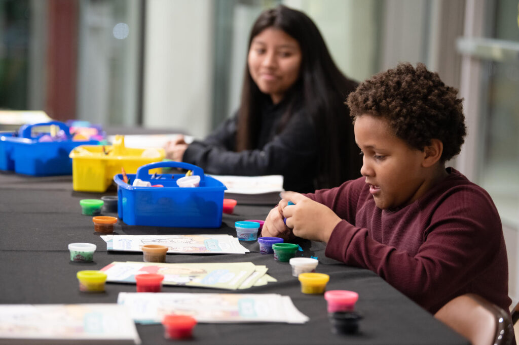 This image shows a young boy fingerpainting at the Desmond Center for Community Engagement and Wellness's Winter Wellness Day on December 8, 2022.