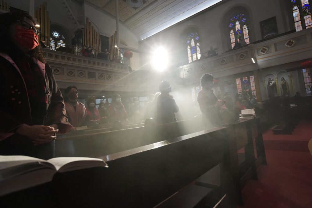 Smoke from incense fills the air as people gather for a Mandarin-language Mass Feb. 6, 2022, at Transfiguration Church in the Chinatown section of New York City.