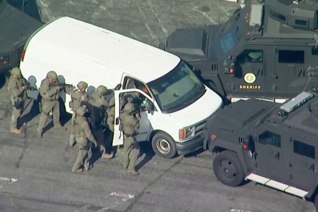 Police use armored vehicles to surround a white cargo van, believed by law enforcement to be connected to the mass shooting in Monterey Park, Calif., according to an ABC affiliate, as a SWAT team approaches at a parking lot in Torrance, Calif., Jan. 22, 2023, in a still image from video.