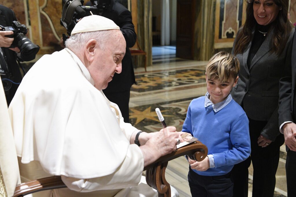 Pope Francis signs an autograph for a boy at the end of an audience with members of the Roman Rota, a Vatican court, Rota employees and members of their families Jan. 27, 2023.
