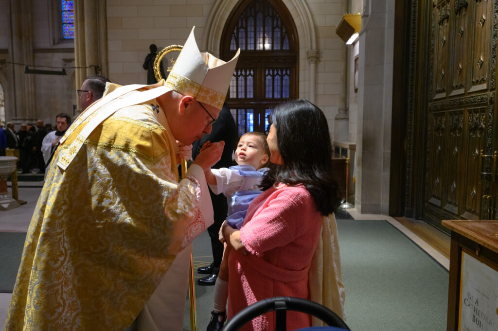 Cardinal Timothy Dolan greets a very young parishioner at St. Patrick's Cathedral, April 9, 2023.