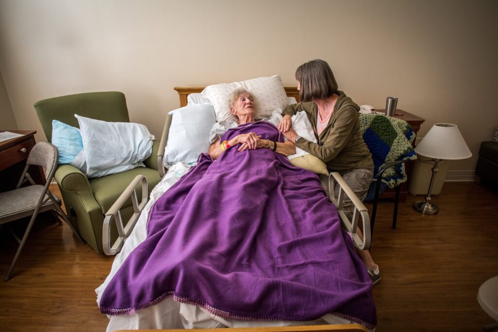 A woman sits at the bedside of her mother in 2016 at de Greeff Hospice House in St. Louis.