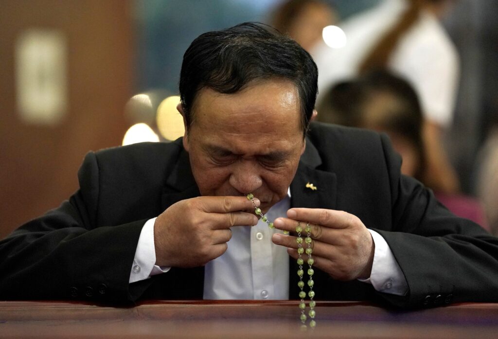 A man kisses a rosary as he prays before Mass in 2018 at a church in Beijing.