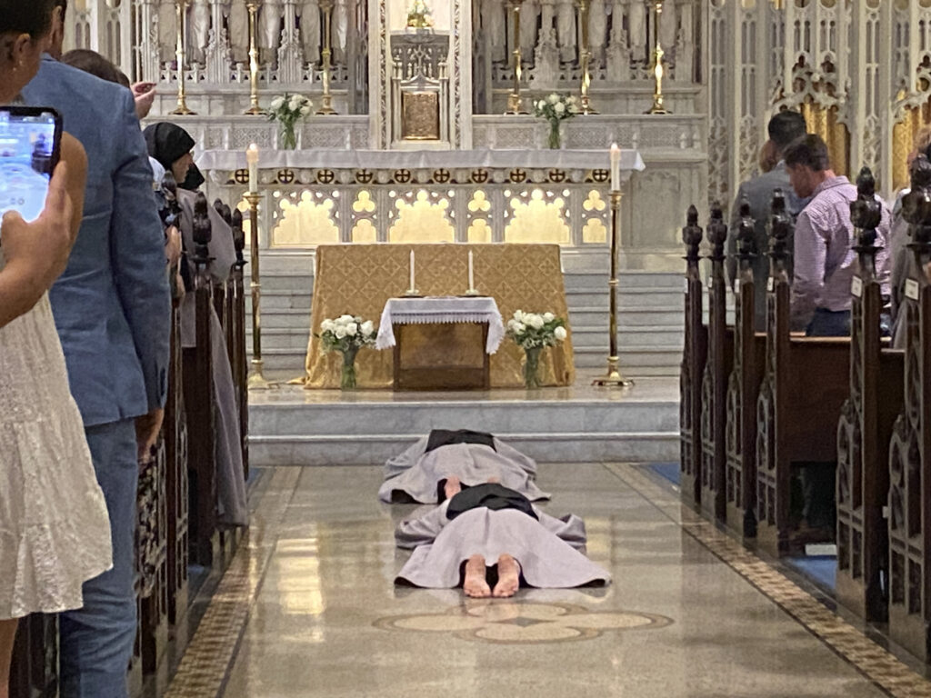 Two sisters of the Franciscan Sisters of the Renewal prostrate themselves before the altar at Our Lady of Good Counsel in Manhattan at their vows Mass, May 13, 2023.