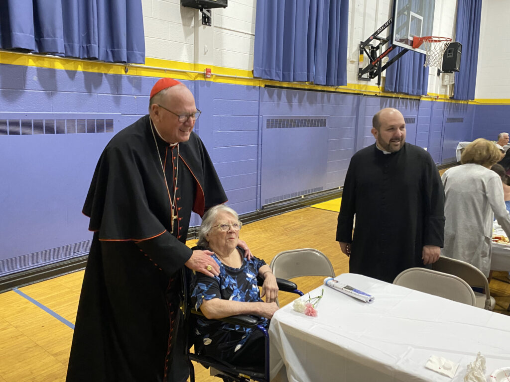 Cardinal Timothy Dolan (left) and Father James Ferreira greet a parishioner of Our Lady of Christian Help in Tottenville, Staten Island, May 13, 2023.