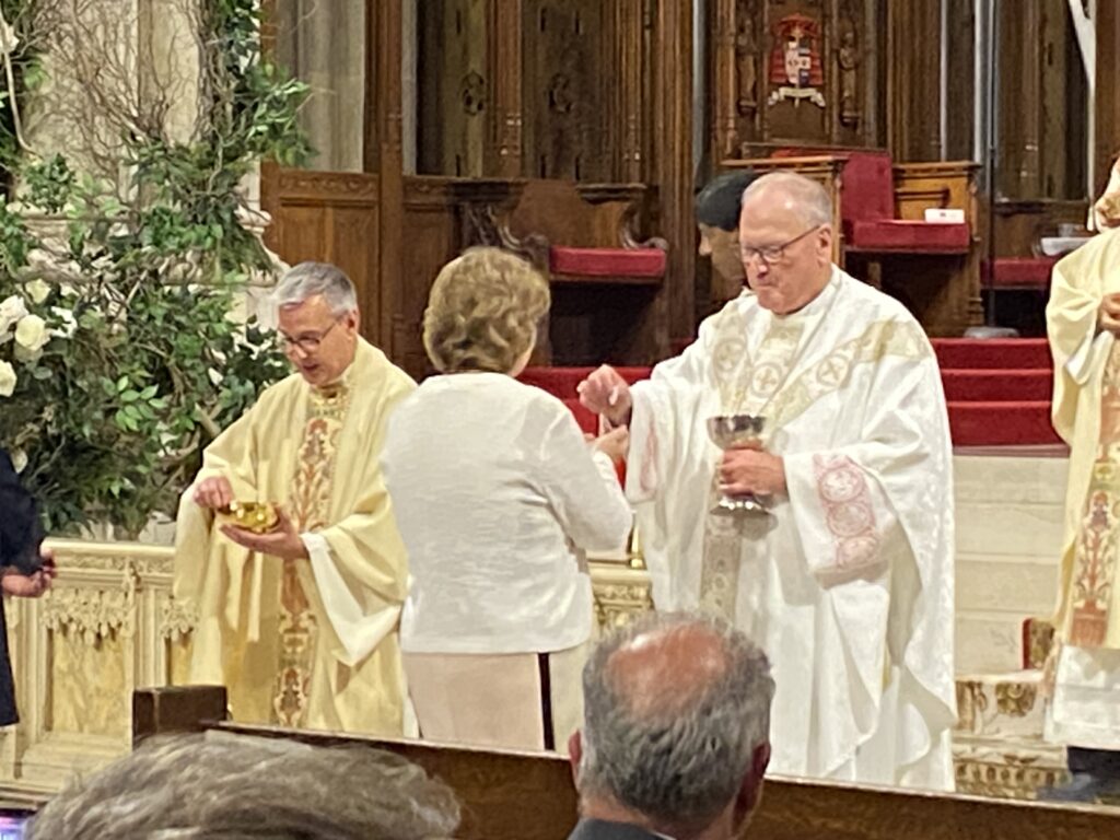 Cardinal Timothy Dolan (right) distributes communion during the annual White Mass, in honor of ArchCare and healthcare workers, May 31, 2023, at St. Patrick's Cathedral.