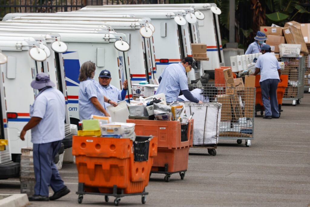 U.S. postal workers load their trucks as they begin their day in Carlsbad, Calif., Aug.17, 2020.