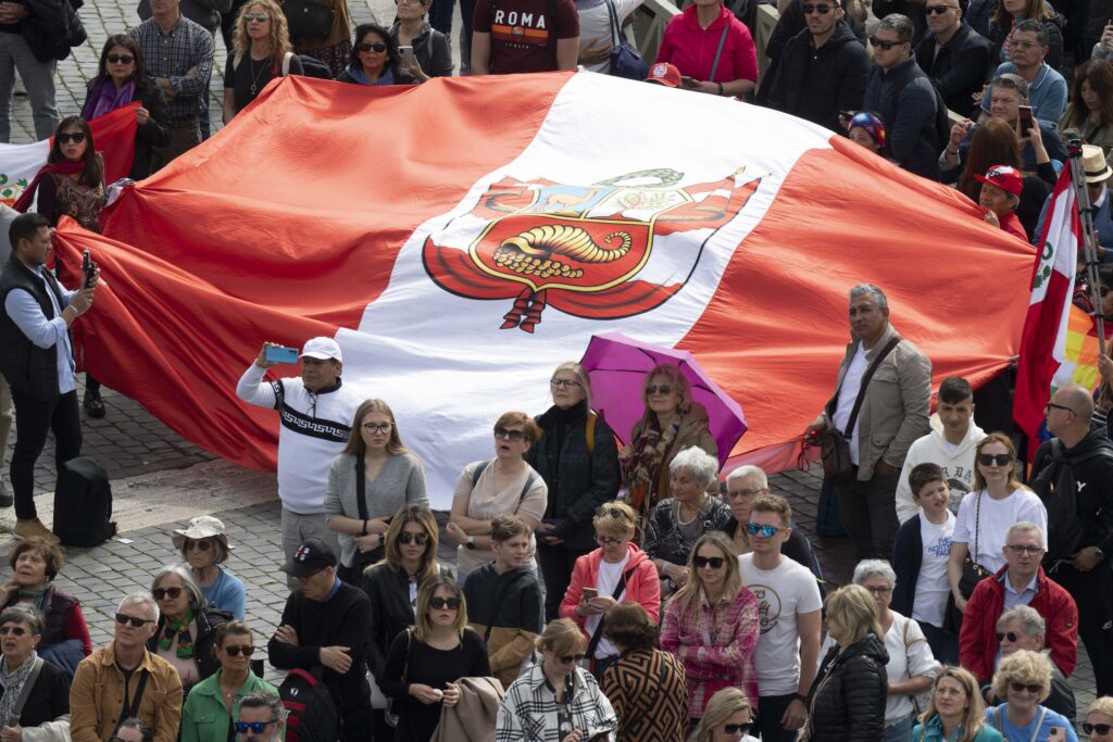 Visitors hold up a flag from Peru in St. Peter's Square at the Vatican March 26, 2023.