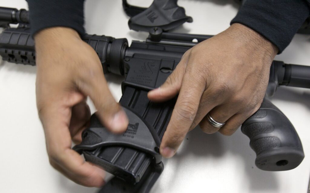 A police officer is pictured in a file photo dismantling a Bushmaster semiautomatic assault rifle after it was turned in during a gun buyback event.