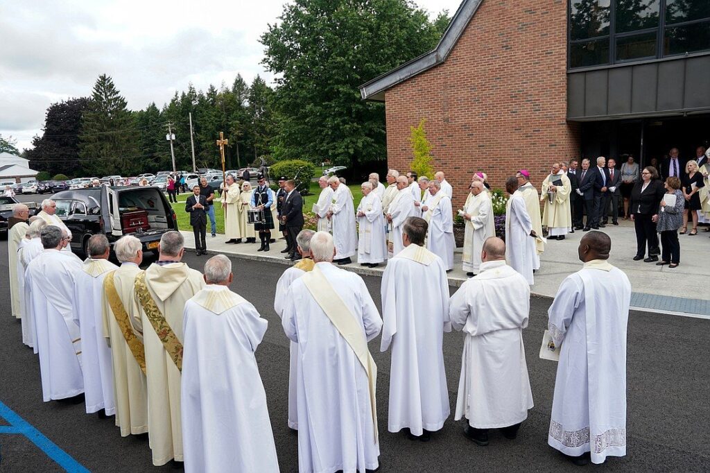 Priests and deacons pay homage to the late Bishop Emeritus Howard J. Hubbard of Albany, N.Y., after his casket is placed in a hearse following his funeral Mass Aug. 25, 2023, at St. Pius X Church in Loudonville.