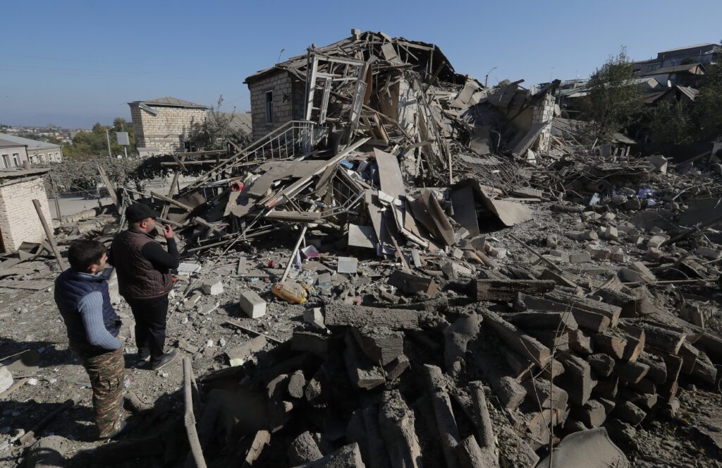 Men look at the ruins of a house in Stepanakert, Azerbaijan, Oct. 17, 2020, following recent shelling during a military conflict over the breakaway region of Nagorno-Karabakh.