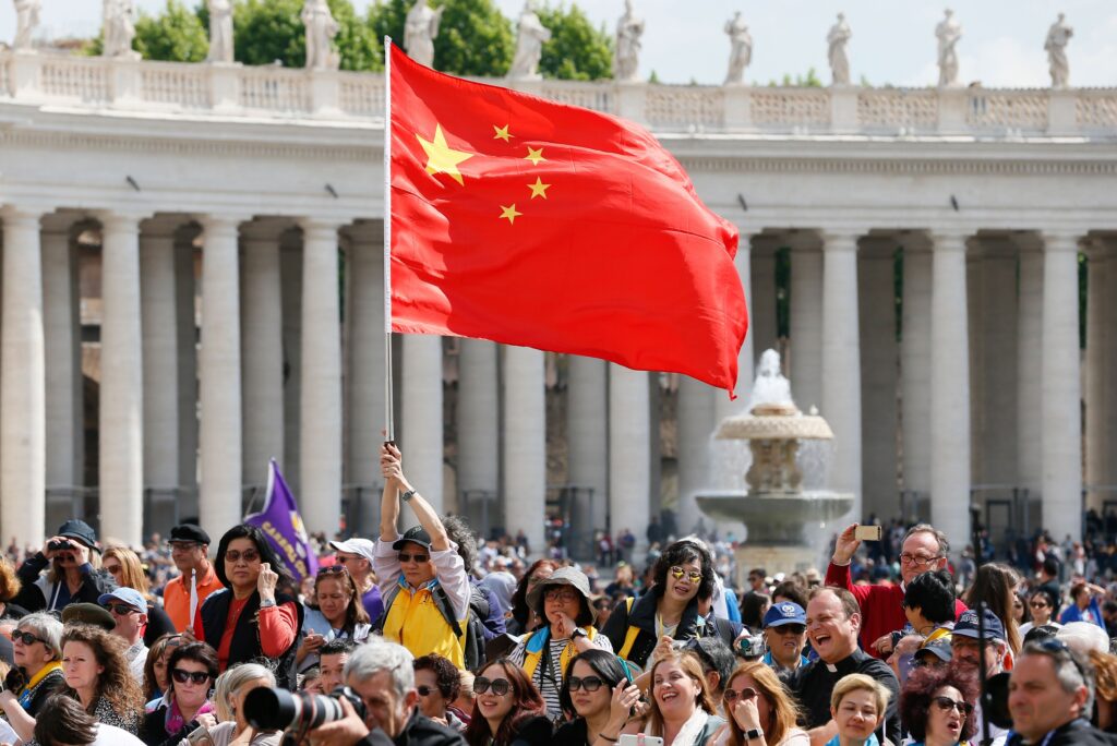 En esta foto de archivo, un visitante ondea la bandera de China mientras que el Papa Francisco lidera la audiencia general en la Plaza de San Pedro en el Vaticano, el 22 de mayo, 2019.