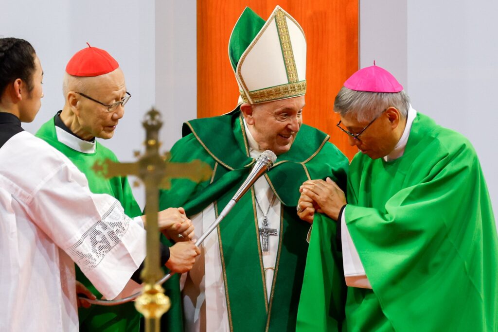 Pope Francis grasps the hands of retired Cardinal John Tong Hon of Hong Kong, left, and Cardinal-designate Stephen Chow Sau-Yan of Hong Kong, right, as he introduces them to people attending his Mass in the Steppe Arena in Ulaanbaatar, Mongolia, Sept. 3, 2023.
