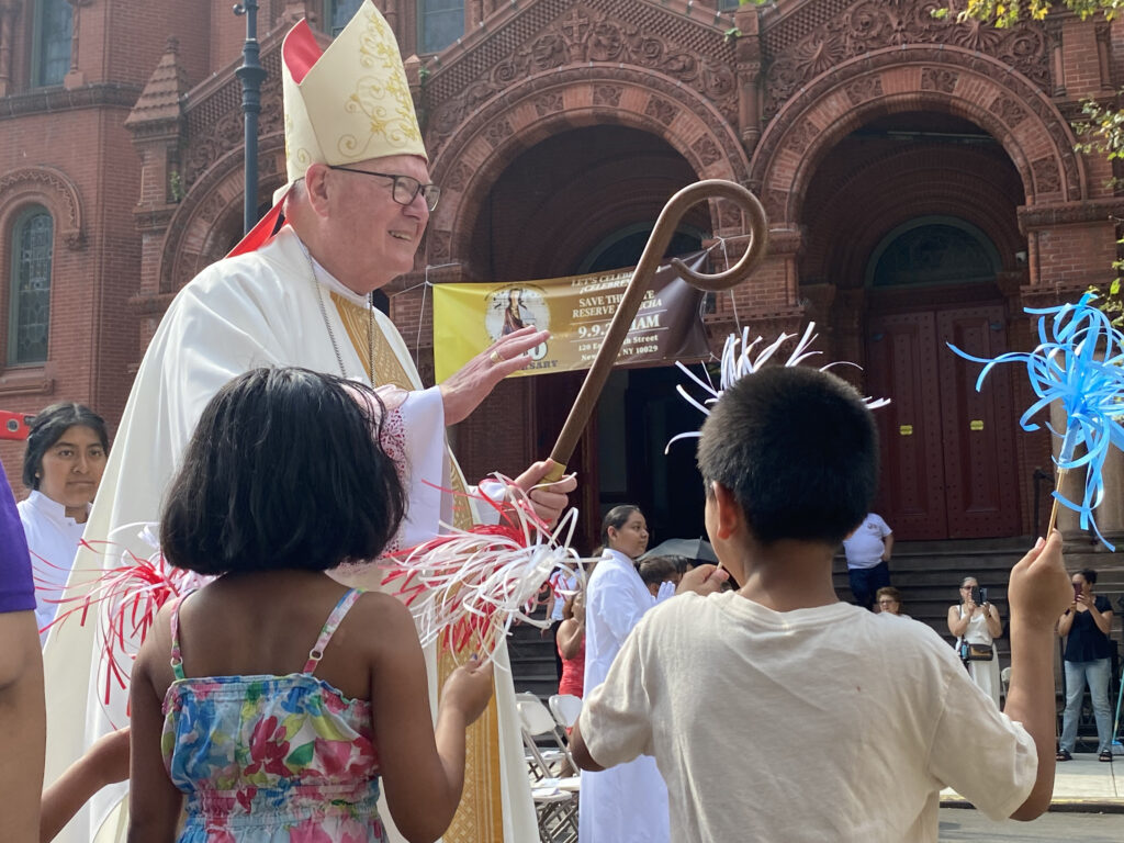 Children welcome Cardinal Timothy Dolan as he processes toward an outdoor altar at 150th-anniversary celebrations for St. Cecilia Church, September 9, 2023.