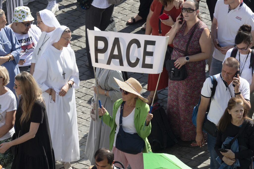 Una mujer sostiene un cartel que dice "Pace", paz en italiano, mientras el Papa Francisco pide el fin de la violencia entre Israel y Palestina después de recitar la oración del Ángelus el 8 de octubre de 2023, con los visitantes en la Plaza de San Pedro en el Vaticano.