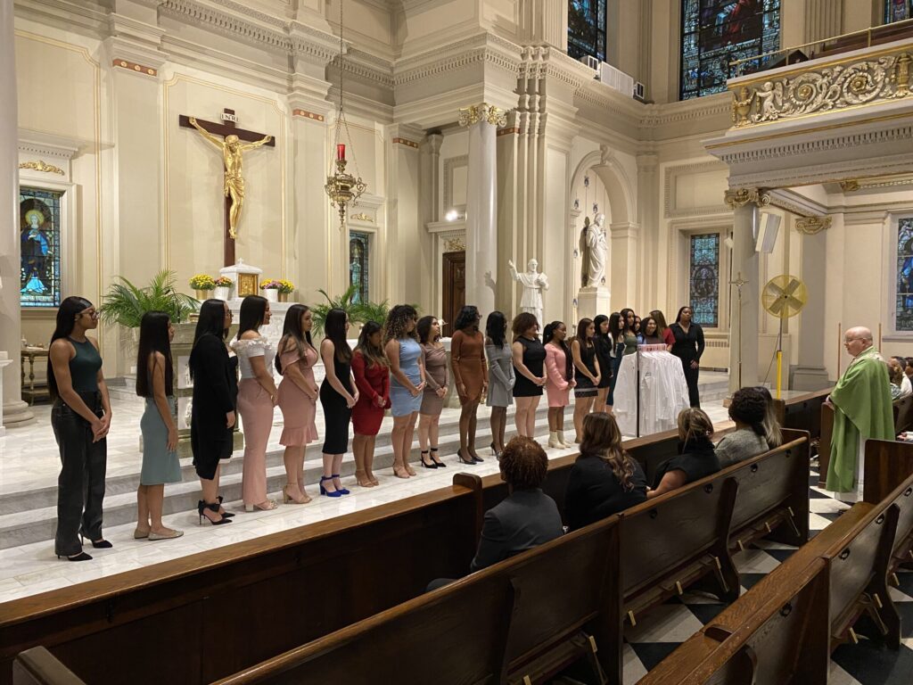 Cathedral high school seniors listen to the blessing of ceremonial white coats by Father Philip J. Kelly, pastor of St. Francis de Sales in Manhattan, October 20, 2023. Photo by Steven Schwankert/The Good Newsroom.