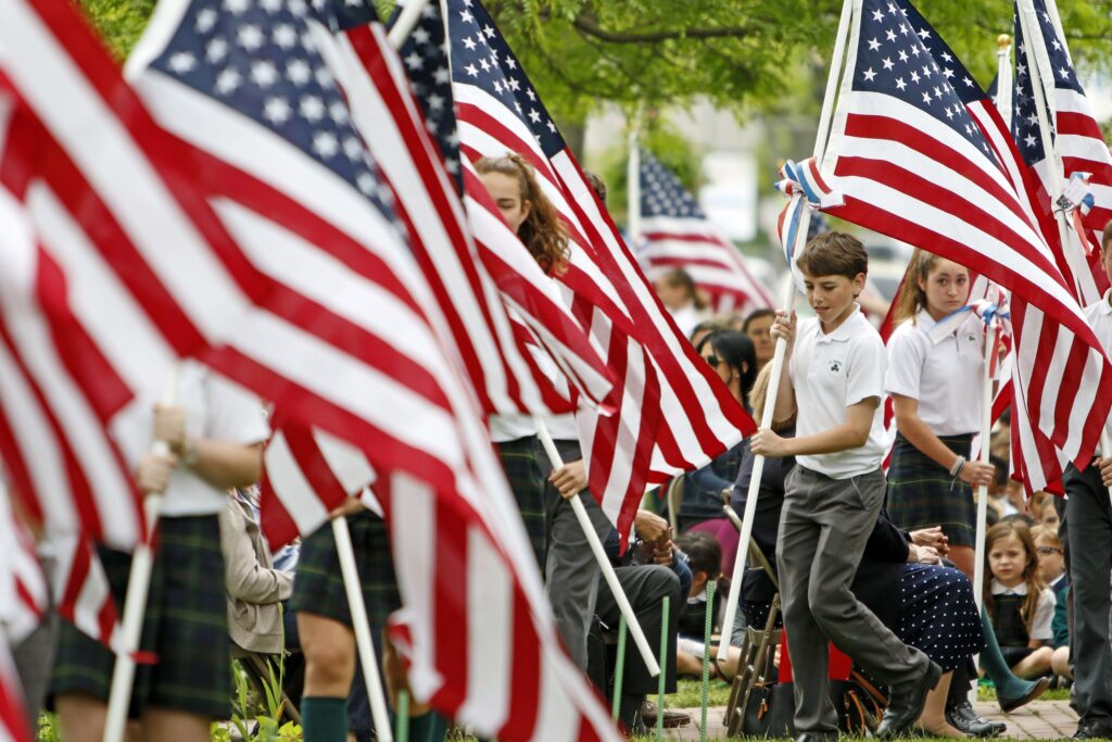 Students at St. Patrick School in Bay Shore create a Field of Honor for living and deceased veterans of the U.S. armed forces as they place 100 U.S. flags on the school's front lawn, May 24, 2017. U.S. bishops hope to better engage young people with the Church through the Institute on the Catechism being launched Nov. 10-12, 2022, just ahead of their fall general assembly in Baltimore.