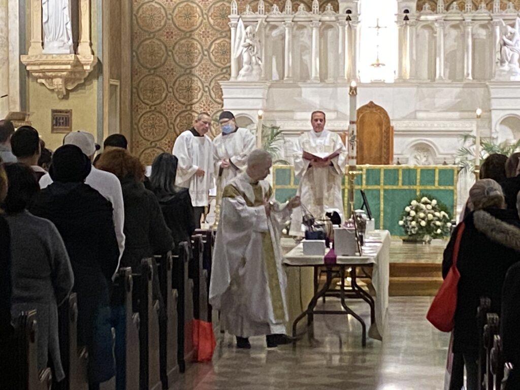 Father Daniel S. Kearney (foreground), pastor of The Church of the Ascension in Manhattan, offers final blessings on 17 urns at a communal burial Mass held November 18, 2023.