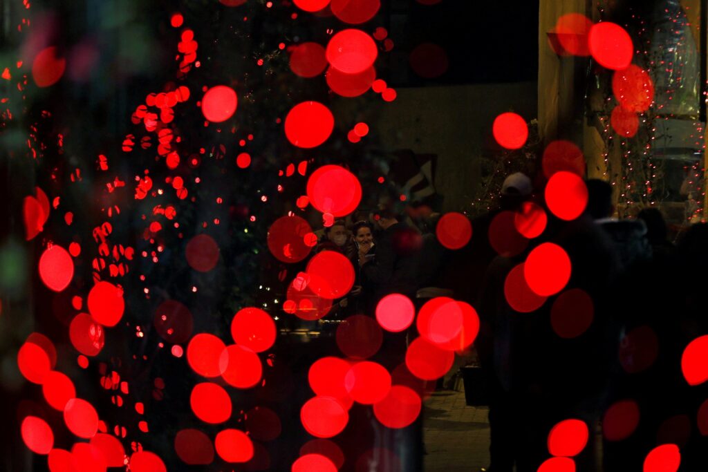 People in Fuhais, Jordan, walk near Christmas lights December 24, 2020, amid the coronavirus pandemic.