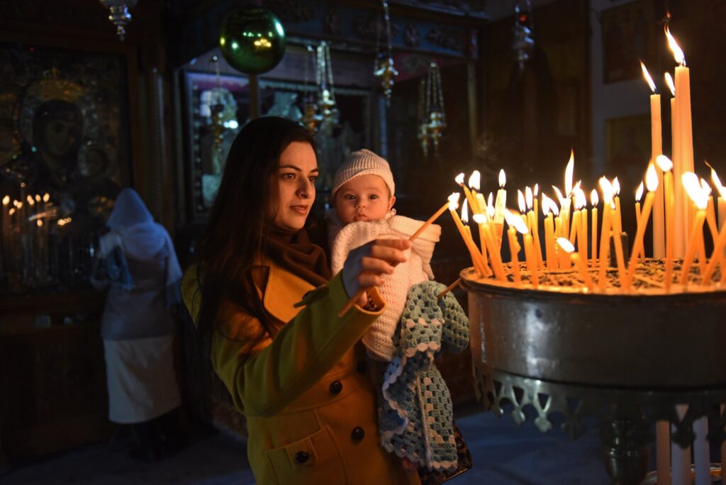 Palestinian Manan Abu Abuayash holds her baby Maram, six months, while lighting candles December 20, 2015, in the Church of the Nativity where tradition believes Christ was born in Bethlehem, West Bank. Advent is a time of anticipation and deep consolation.