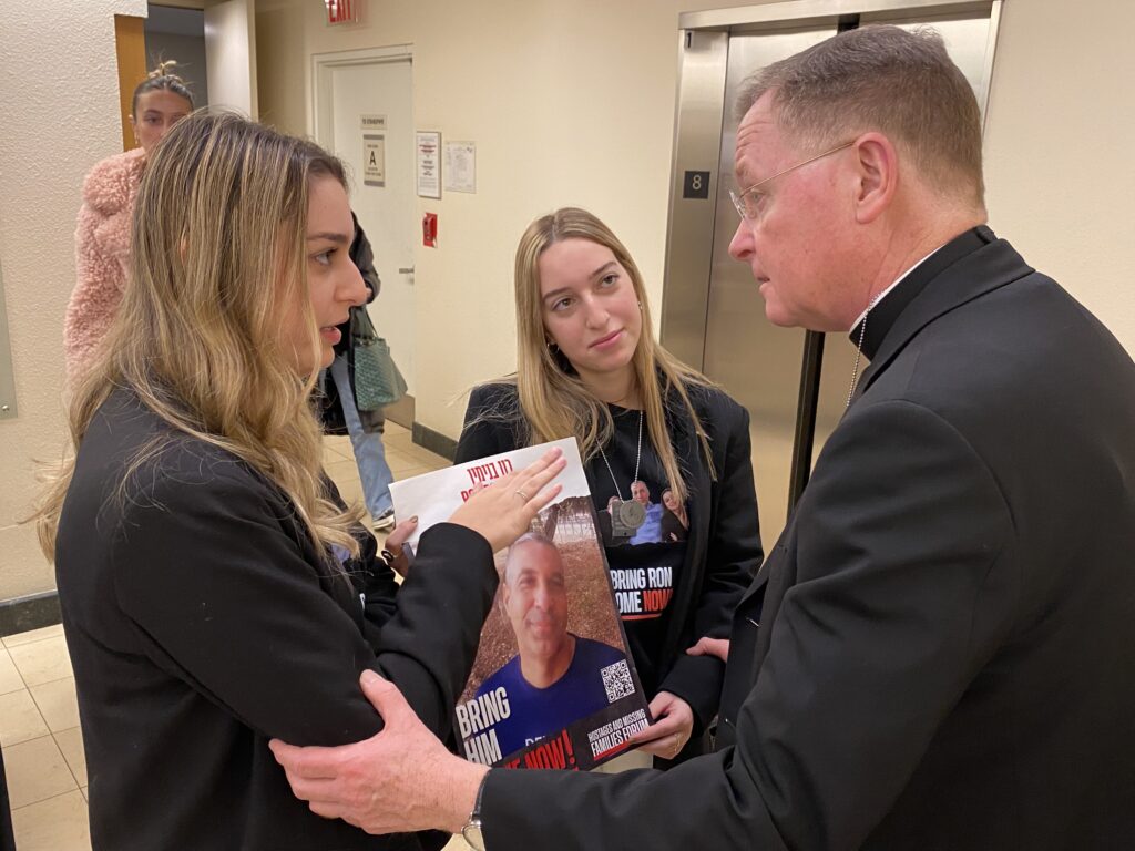 Archdiocese of New York Auxiliary Bishop Edmund Whalen (right) consoles the daughters of Israeli hostage Ron Benjamin, on December 13, 2023.