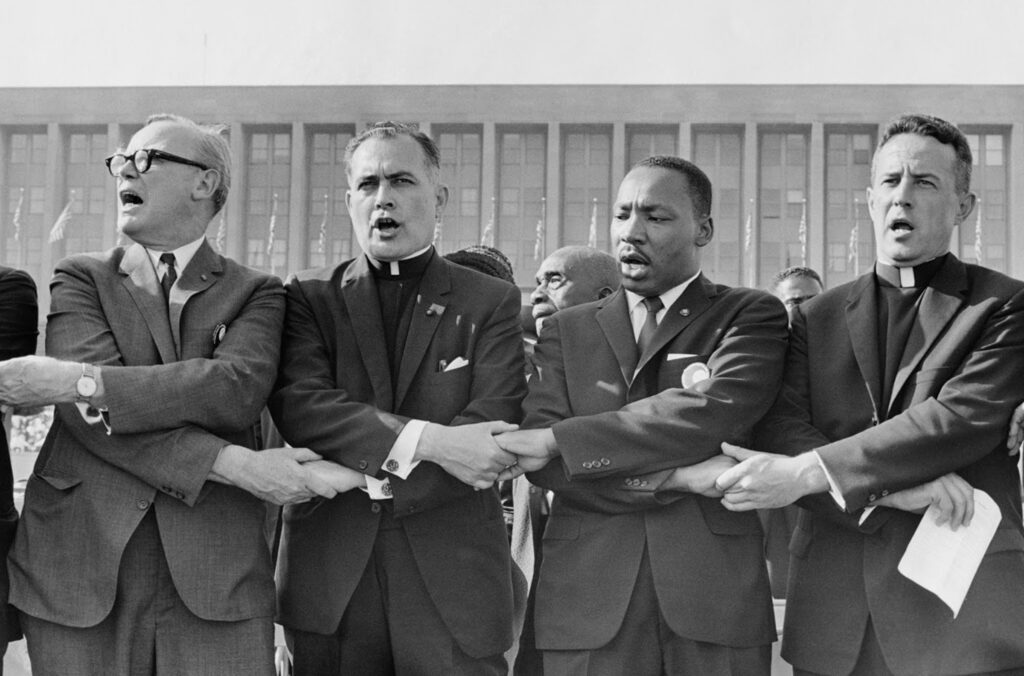 Holy Cross Father Theodore Hesburgh, then president of the University of Notre Dame, second from left, joins hands with the Reverend Dr. Martin Luther King Jr., the Reverend Edgar Chandler, and Monsignor Robert J. Hagarty of Chicago, far right, in this 1964 file photo.