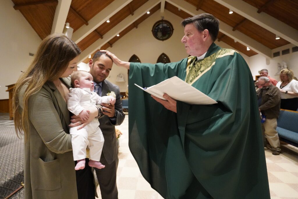Christina and Julio Prendergast hold their five-month-old son, Gabriel James, as the couple receives a blessing from Monsignor Frank Schneider during the baby's baptismal ceremony Nov. 12, 2022, at St. John the Baptist Church in Wading River, N.Y.