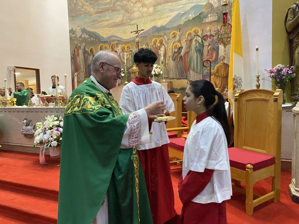 Cardinal Timothy Dolan (left) offers communion to an altar server at St. Martin of Tours parish in The Bronx, February 11, 2024.