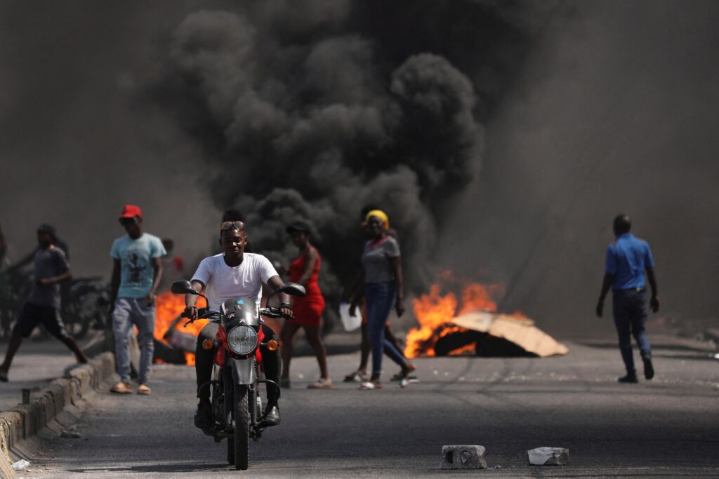 A man drives past a burning barricade during a protest against Haitian Prime Minister Ariel Henry's government and insecurity in Port-au-Prince March 1, 2024.