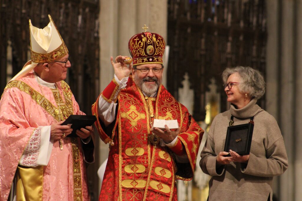 New York Cardinal Timothy M. Dolan and Regina Lynch, the new executive president of Aid to the Church in Need, look on as Major Archbishop Shevchuk of Kyiv-Halych, head of the worldwide Ukrainian Greek Catholic Church, displays a traditional Ukrainian Easter egg during a Mass of thanksgiving for Aid to the Church in Need at St. Patrick’s Cathedral in New York City March 10, 2024.