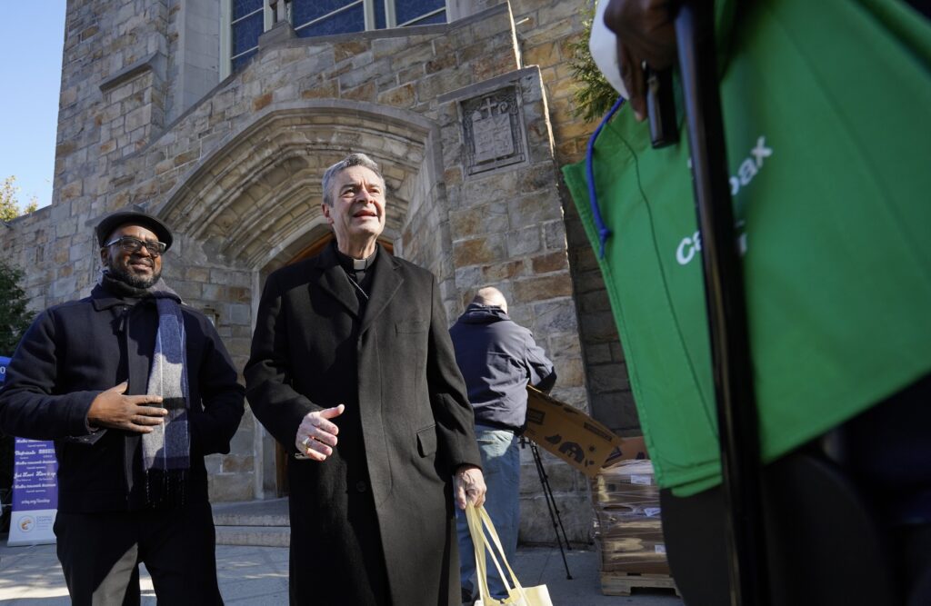 Father Lucon Rigaud (left), pastor of Holy Innocents Parish in the Flatbush section of Brooklyn, and Bishop Robert J. Brennan of Brooklyn, are pictured helping distribute frozen turkeys and other food outside the church Nov. 21, 2022.