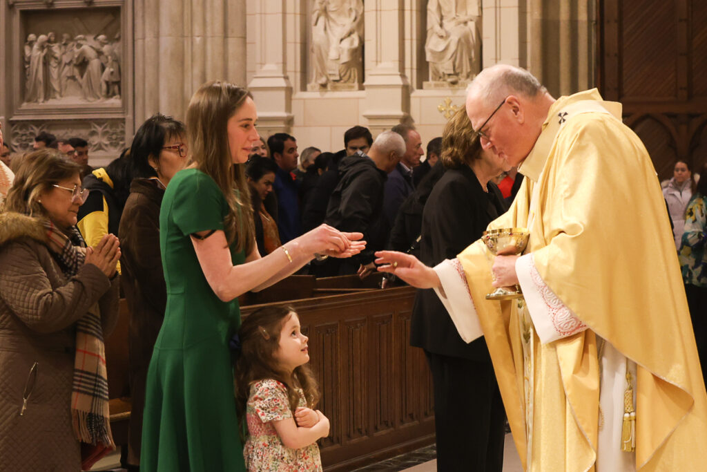 Cardinal Timothy Dolan (right) blesses a child during the distribution of holy communion at the Mass of the Lord's Supper at St. Patrick's Cathedral, March 28, 2024.