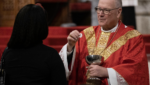 Cardinal Timothy Dolan (right) distributes communion during Palm Sunday Mass at St. Patrick's Cathedral in Manhattan, March 24, 2024.