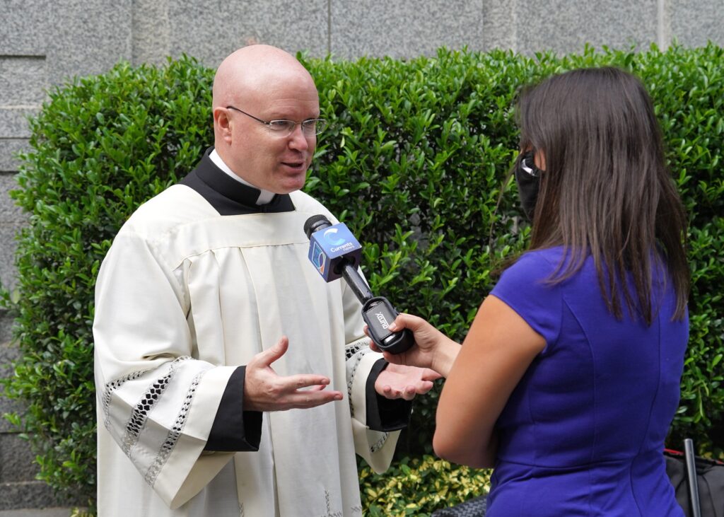 Father Roger Landry (left), formerly the attaché to the Vatican's Permanent Observer Mission to the United Nations and now the Catholic chaplain at Columbia University in Manhattan, speaks with reporter Emily Drooby of NET TV, of the Diocese of Brooklyn before a prayer service for U.N. diplomats September 14, 2020, at Holy Family Church in New York City.