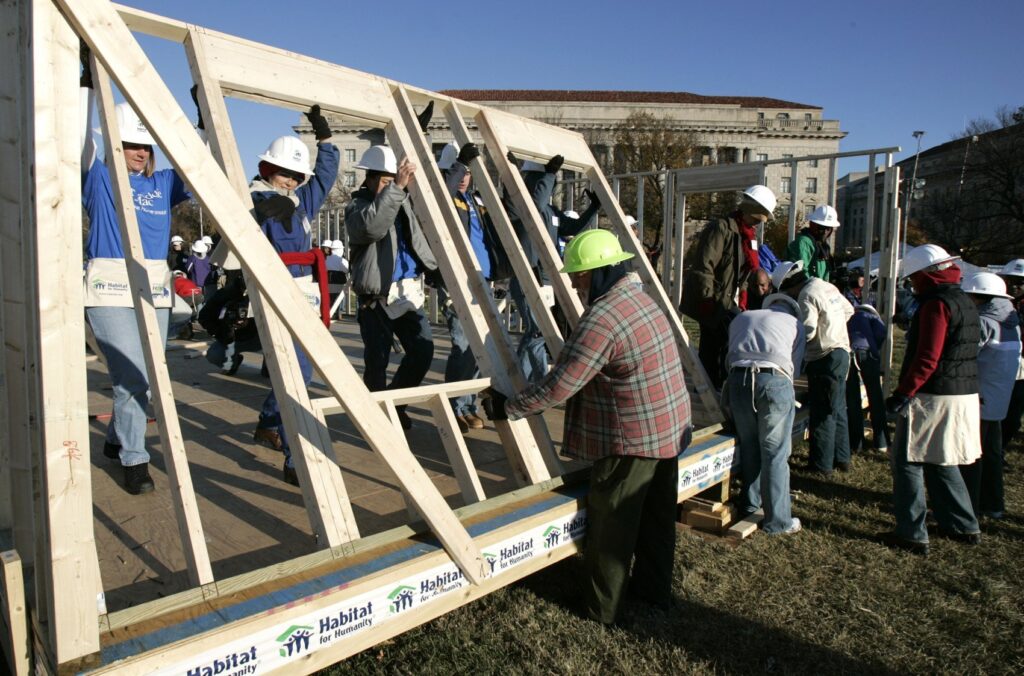 Volunteers for Habitat for Humanity raise a wall frame in this November 18, 2005 file photo.
