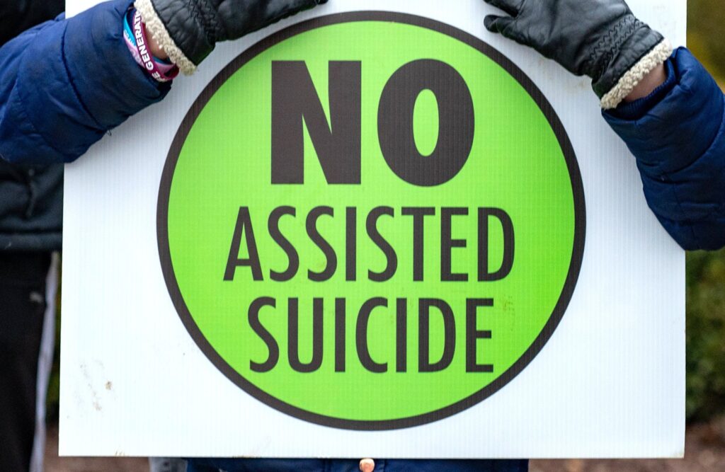 A person is pictured in a file photo holding a sign against physician-assisted suicide.