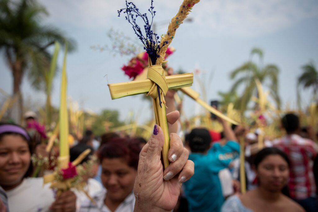 La gente levanta sus hojas de palma para que sean bendecidas durante una Misa de Domingo de Ramos 24 de marzo 2024, en Managua, Nicaragua.