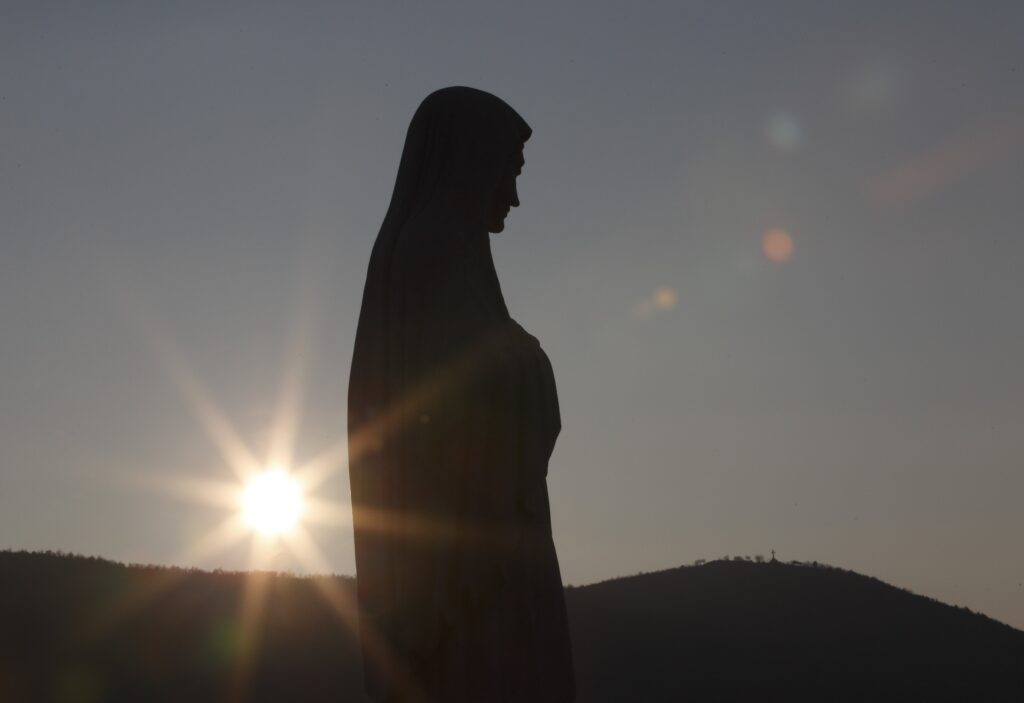The sun sets behind a statue of Mary on Apparition Hill in Medjugorje, Bosnia-Herzegovina, in this February 26, 2011, file photo.