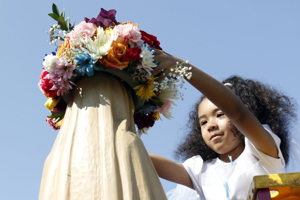 A child is pictured in a file photo placing a crown of flowers atop a statue of Mary during a prayer service celebrated in honor of Mary at Our Lady of Lourdes School in West Islip, N.Y.