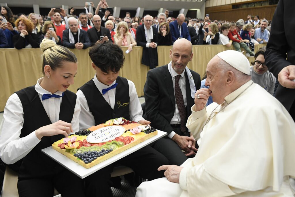 Pope Francis tastes the fruit of the labors of two young chefs after a meeting with an Italian federation of Catholic religious orders and other groups that provide job training to young people May 3, 2024, in the Paul VI Audience Hall at the Vatican.