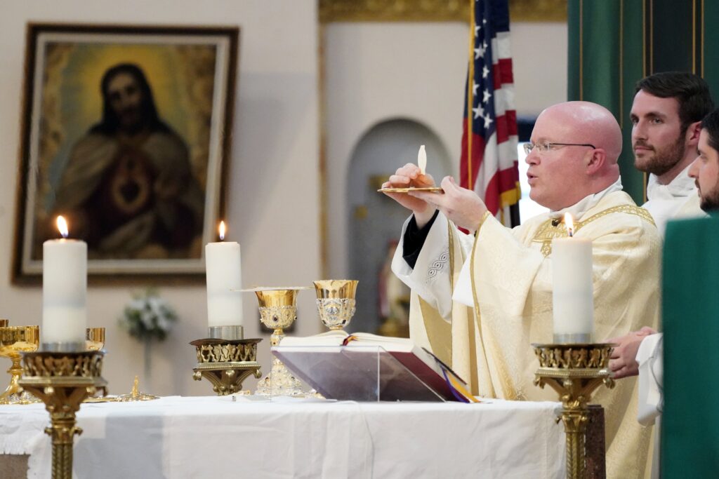 Father Roger Landry, chaplain at Columbia University, elevates the Eucharist during Mass at Sacred Heart of Jesus Church in New York City October 11, 2022.
