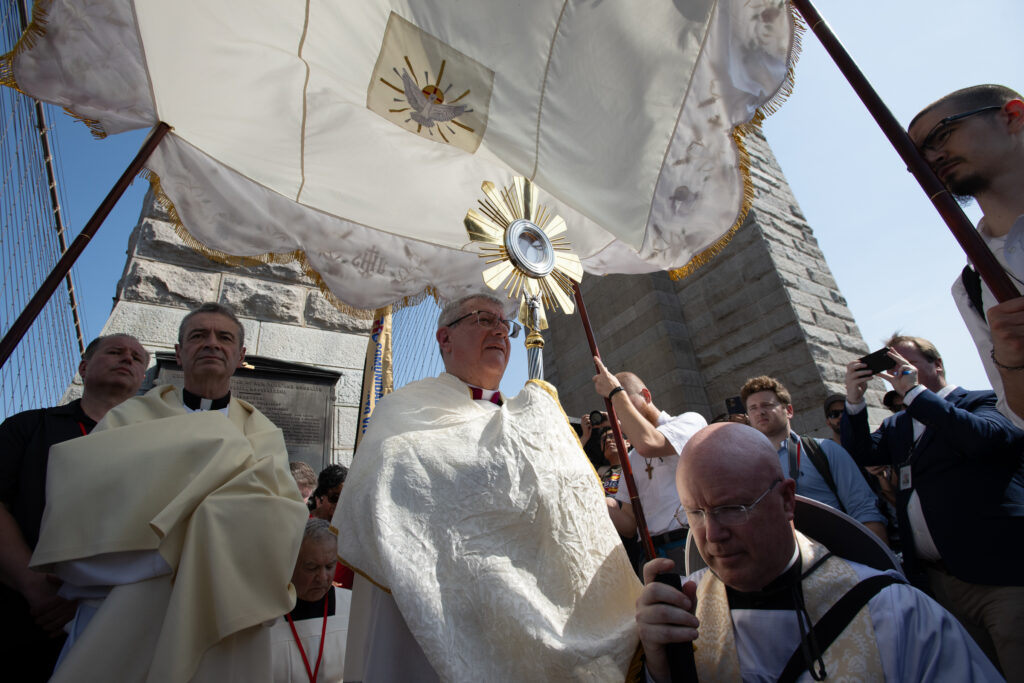 Archdiocese of New York Auxiliary Bishop Gerardo Colacicco (center, holding monstrance) blesses pilgrims from Manhattan, as he prepares to hand the Blessed Sacrament to Bishop of Brooklyn Robert Brennan (left), as Father Roger Landry (right) kneels, May 26, 2024.