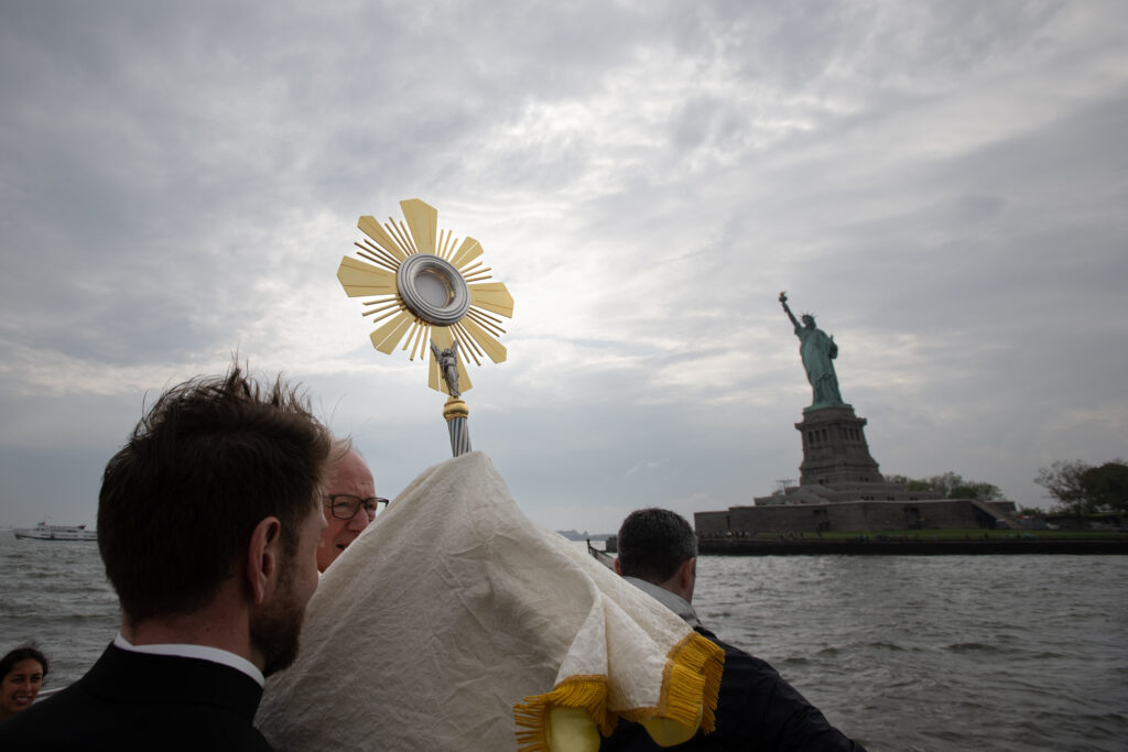 Cardinal Timothy Dolan (center, holding monstrance) offers a benediction in front of the Statue of Liberty on Liberty Island in New York Harbor,on May 27, 2024.
