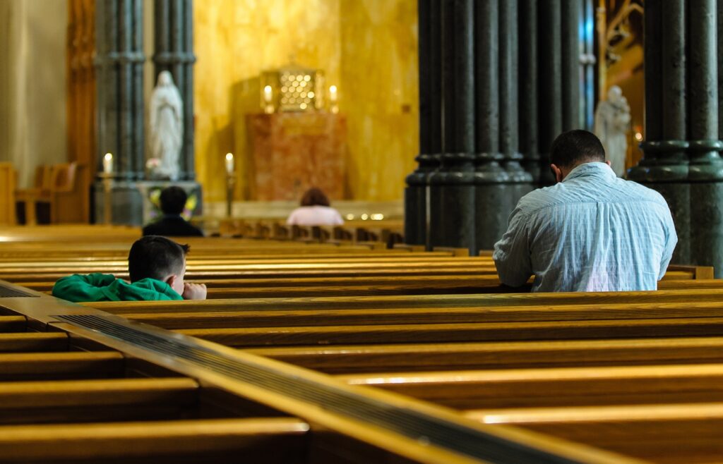 A child watches his father pray inside the Cathedral of Saints Peter and Paul in Providence, Rhode Island.