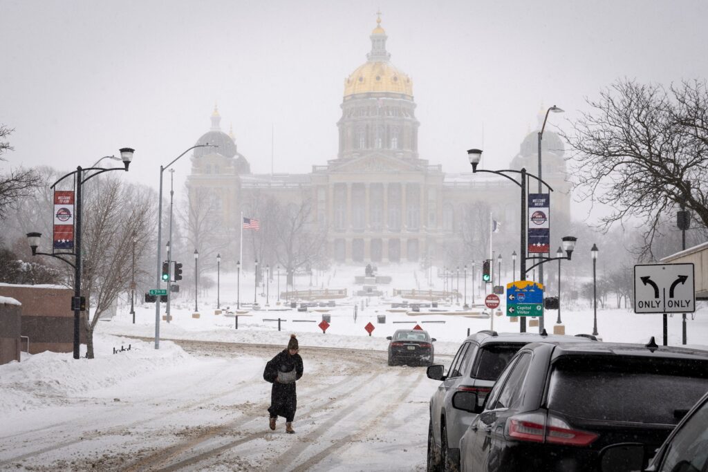 A woman walks in the street in front of the Iowa Capitol in downtown Des Moines Jan. 13, 2024, after a blizzard left several inches of snow.