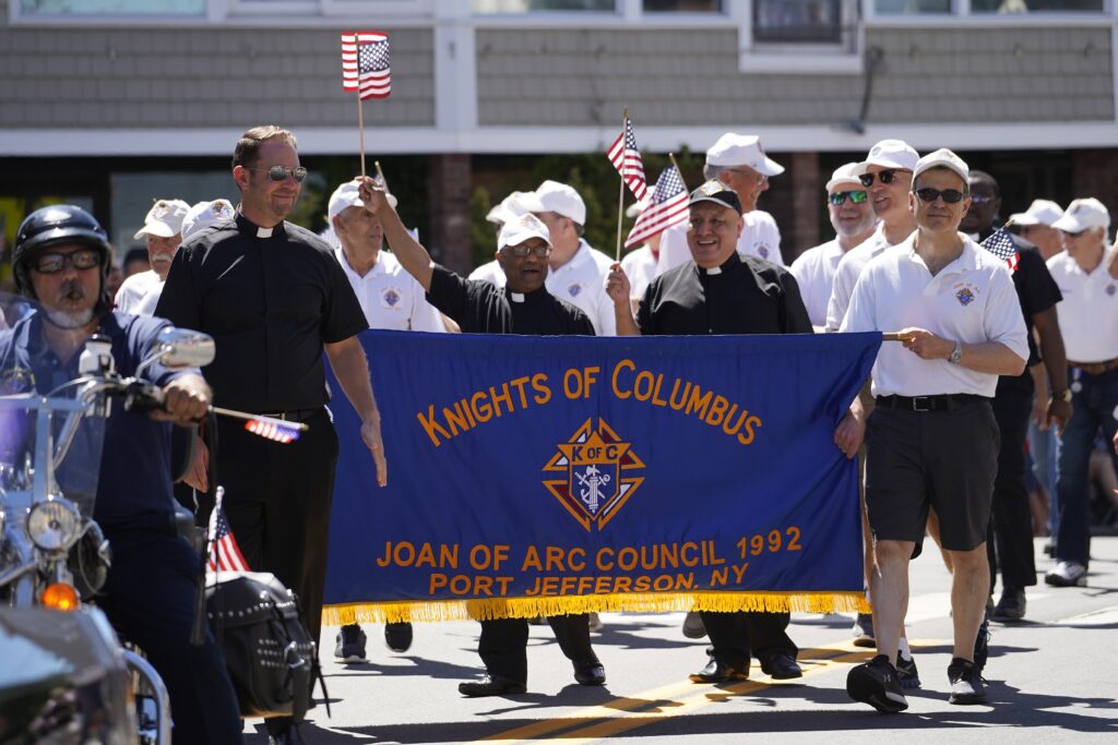 Fathers Gregory Rannazzisi, left, Francis Lasrado and Rolando Ticllasuca of Infant Jesus Church in Port Jefferson, march with the parish's Knights of Columbus Council 1992 in the Independence Day parade in Port Jefferson July 4, 2022.